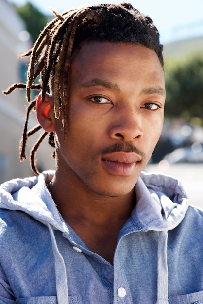 Afrikanischer Mann mit den Dreadlocks, die draußen anstarren