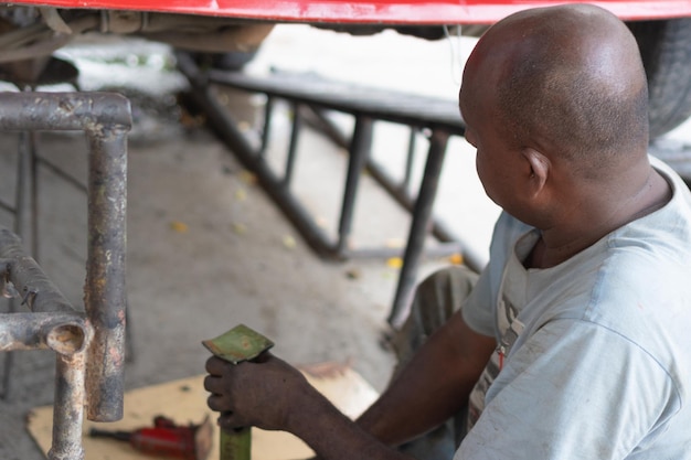 Afrikanischer Mechaniker, der in einer Werkstatt unter dem Fahrzeug arbeitet