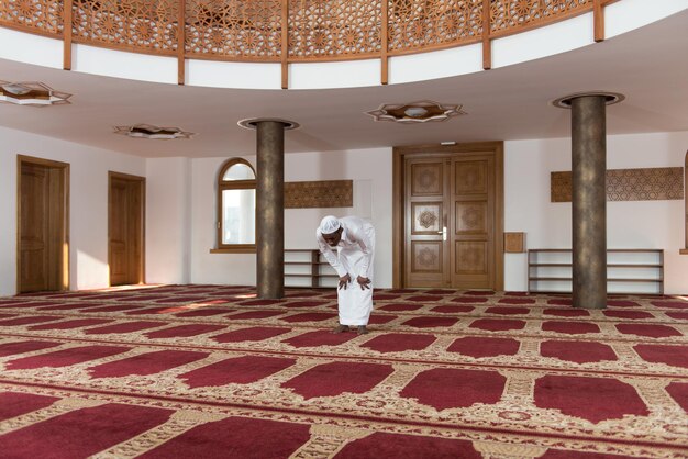 Afrikanischer muslimischer Mann, der traditionelles Gebet zu Gott macht, während er eine traditionelle Kappe Dishdasha trägt