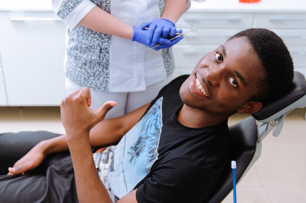 Afrikanischer Patient in der Zahnheilkunde lächelnd im zahnmedizinischen Stuhl