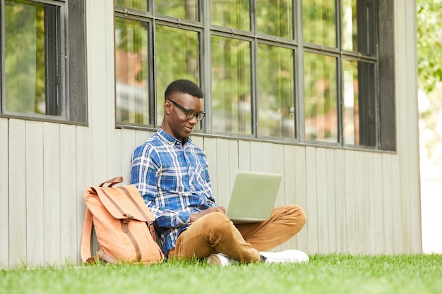 Afrikanischer Student mit Laptop im Freien