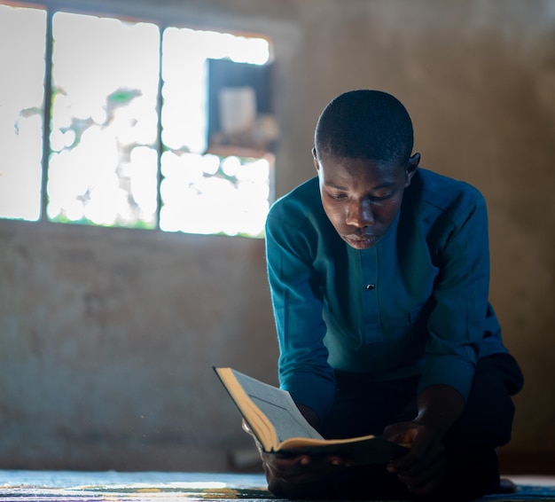 Foto afrikanischer teenager sitzt und liest ein buch in einer armen schule