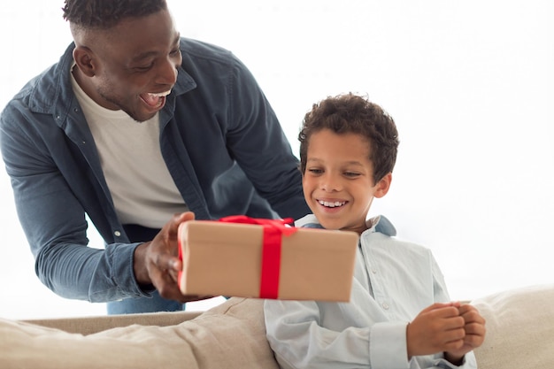 Afrikanischer Vater schenkt seinem kleinen Sohn zu Hause eine Geschenkbox