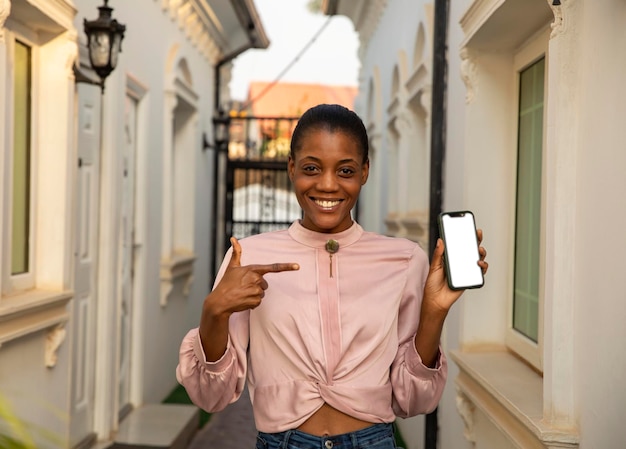 Afrikanisches Mädchen, das auf ein Mockup-Handydisplay zeigt