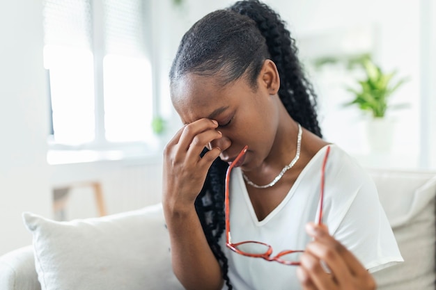 Afrikanisches Mädchen mit Brille reibt sich die Augen, leidet an müden Augen, Augenkrankheiten-Konzept