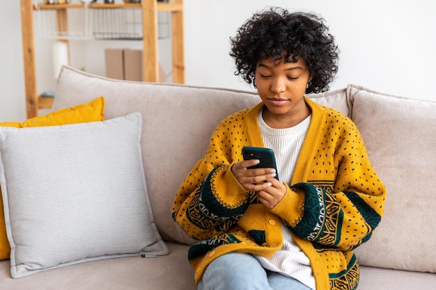 Afrikanisches Mädchen mit Smartphone-Touchscreen, das zu Hause eine Bildlaufseite eingibt Frau mit Handy, die im Internet mit Social-Media-Apps surft und Spiel spielt Online-Shopping Internet-Nachrichten Handysucht