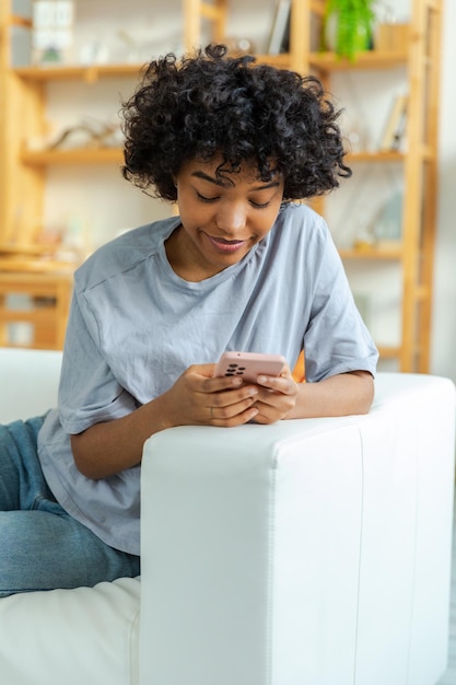 Afrikanisches Mädchen mit Smartphone-Touchscreen-Eingabe-Scroll-Seite zu Hause Frau mit Handy surfin