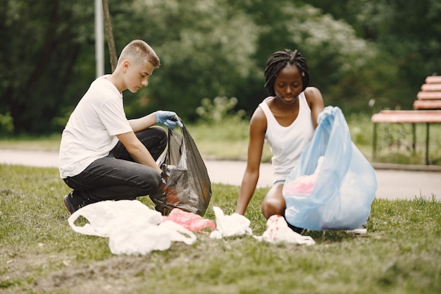 Afrikanisches Mädchen und europäischer Junge pivcking Müll. Aktivisten räumen den Park seitlich.