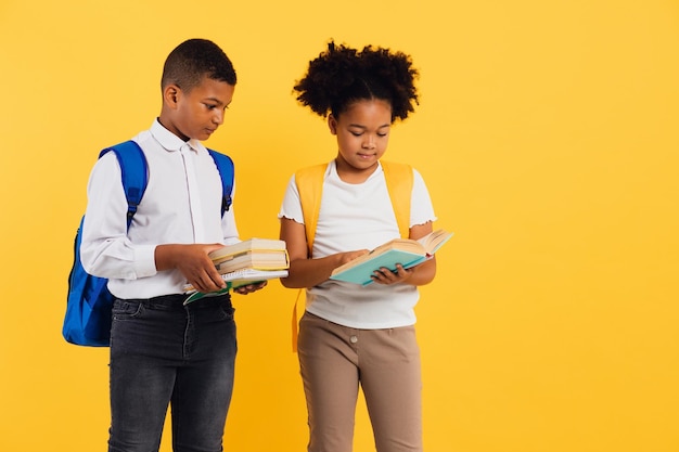 Afro-americana feliz estudante e estudante segurando livros em fundo amarelo espaço de cópia