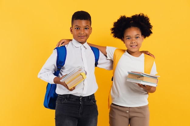 Afro-americana feliz estudante e estudante segurando livros em fundo amarelo espaço de cópia