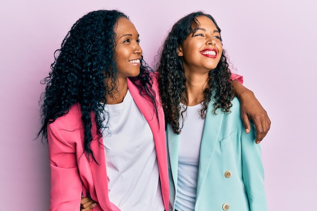 Afro-americana mãe e filha usando estilo de negócios olhando para o lado com sorriso no rosto, expressão natural. rindo confiante.