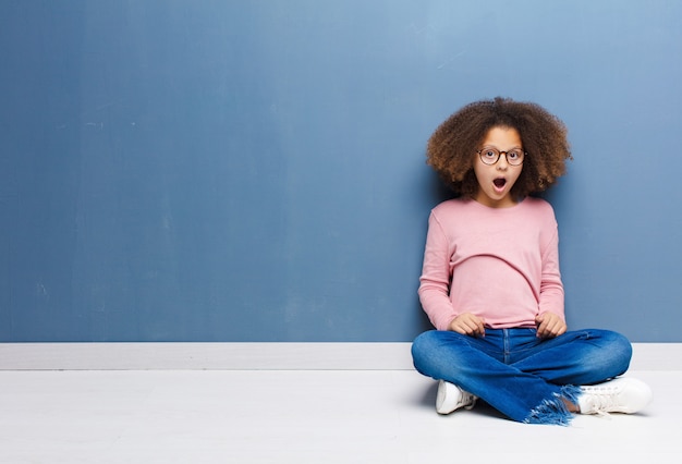 Afro-americana menina olhando chocado sentado no chão