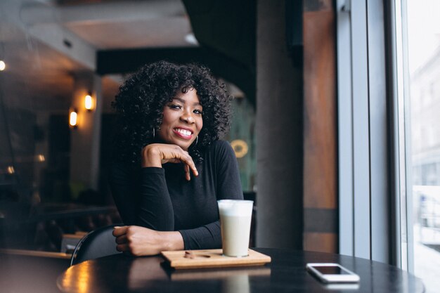 Afro americana mulher com café sentado em um café