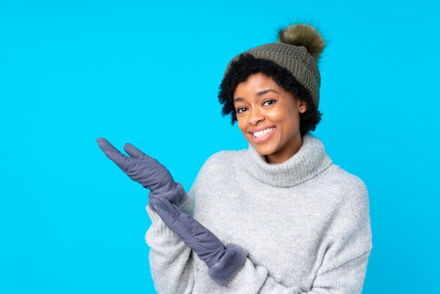 Afro-americana mulher com chapéu de inverno parede azul