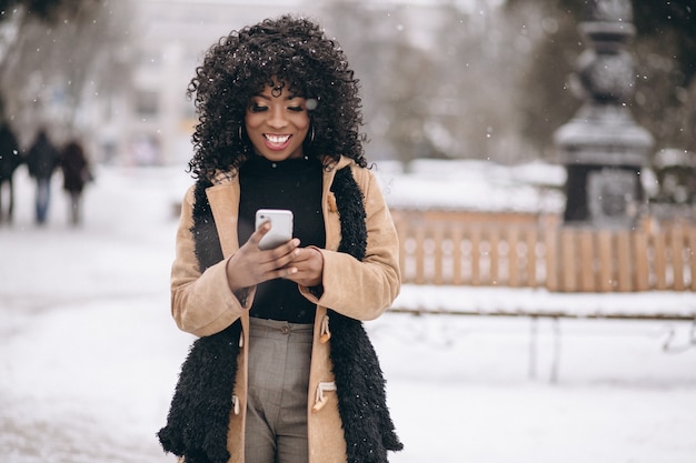 Afro americana mulher com telefone no inverno