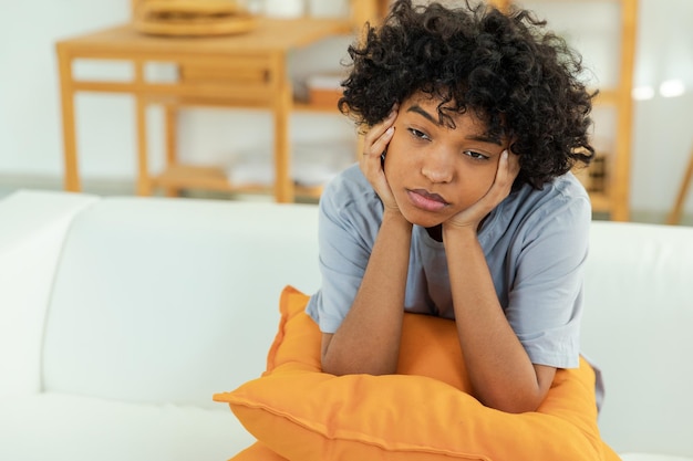 Foto afro-americana, triste e pensativa, em casa, a jovem africana se sente deprimida, ofendida e solitária