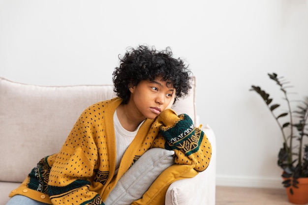 Foto afro-americana, triste, pensativa, pensativa, desmotivada, sentada no sofá em casa, na jovem áfrica