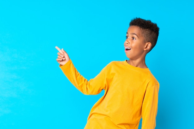 Afro-americano boyblue fundo surpreso e apontando o dedo para o lado