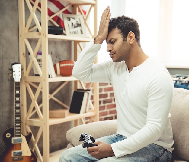 Afro americano está sentado chateado enquanto estiver jogando o jogo.