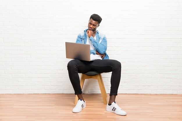 Foto afro americano homem trabalhando com seu laptop em pé e olhando para baixo