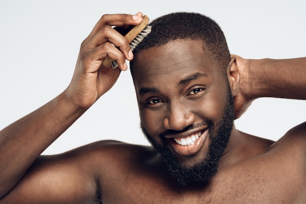 Afro americano sorridente homem penteia cabelo