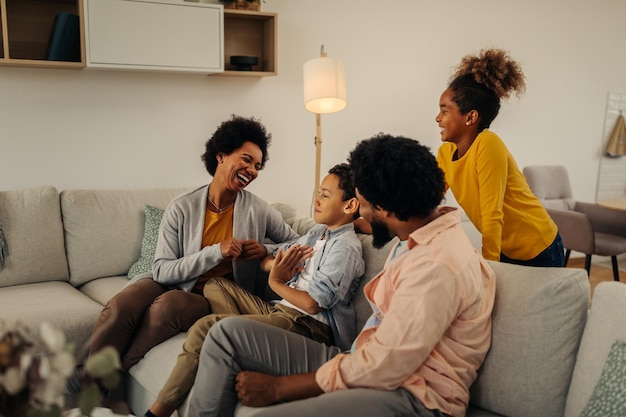 Afro-Eltern und ihre Kinder unterhalten sich, während sie auf dem Sofa im Wohnzimmer sitzen