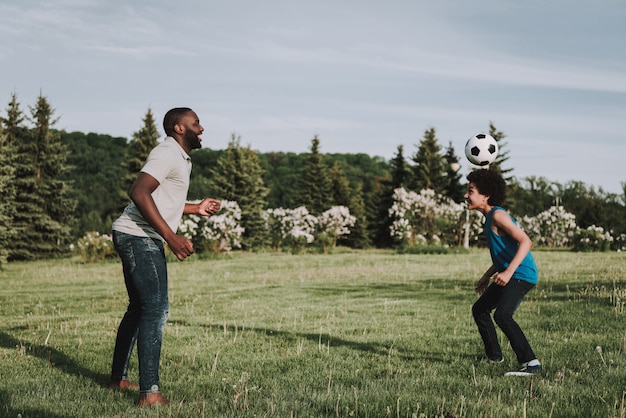 Afro filho e pai brincam juntos na bola na natureza