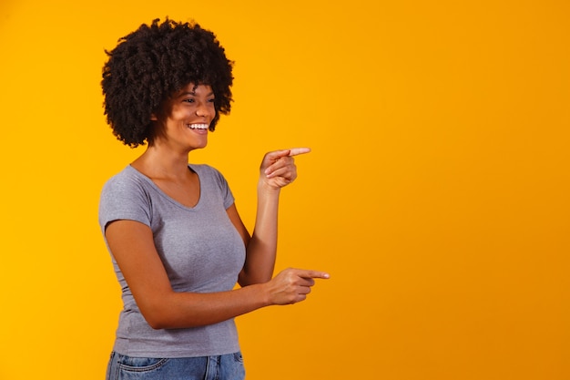 Afro-Frau, die auf Kopienraum auf gelber Wand zeigt