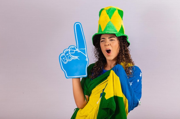 Afro-Frau, die die Kamera mit Fußballhandschuh im brasilianischen Outfit betrachtet.