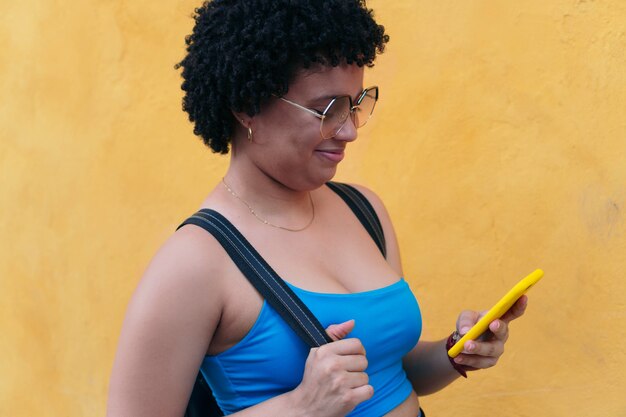 Afro-Frau, die ein Handy benutzt, während sie die Straße entlang geht