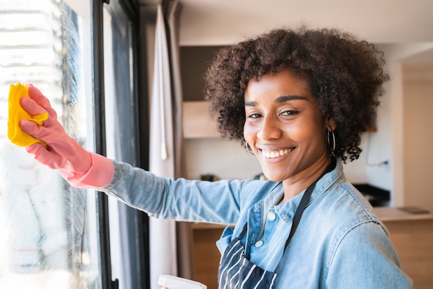 Afro Frau, die Fenster mit Lappen zu Hause putzt