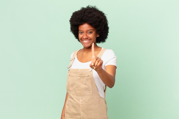 Afro-Frau, die stolz und selbstbewusst lächelt und triumphierend die Nummer eins posiert und sich wie ein Spitzenkoch fühlt