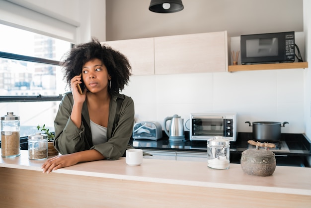 Afro-Frau, die zu Hause am Telefon spricht.