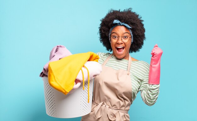 Afro Frau fühlt sich schockiert, aufgeregt und glücklich, lacht und feiert Erfolg, sagt wow!