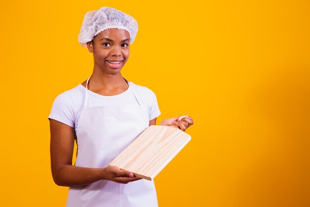 Afro-Frau in Schürze, die ein Fleischbrett mit Platz für Text hält.