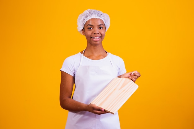 Afro-Frau in Schürze, die ein Fleischbrett mit Platz für Text hält.