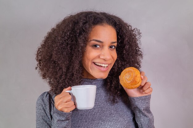 Afro-Frau isst Donuts und trinkt Kaffee