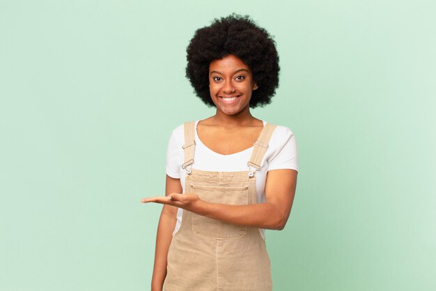Afro-Frau lächelt fröhlich, fühlt sich glücklich und zeigt ein Konzept im Kopierraum mit Handflächenkochkonzept