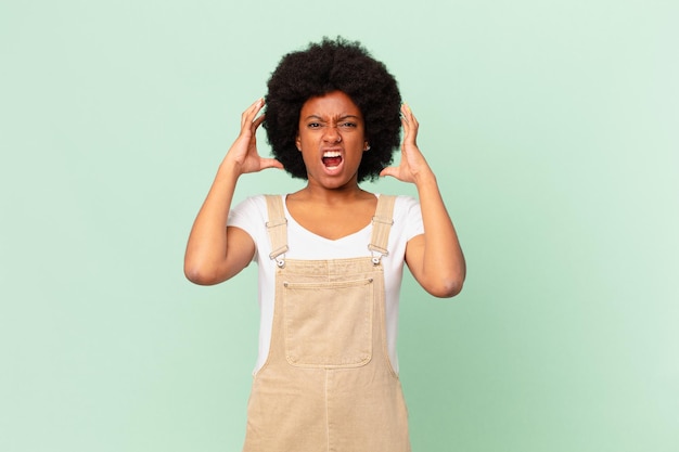 Afro-Frau schreit mit den Händen in die Luft und fühlt sich wütend, frustriert, gestresst und verärgert Kochkonzept