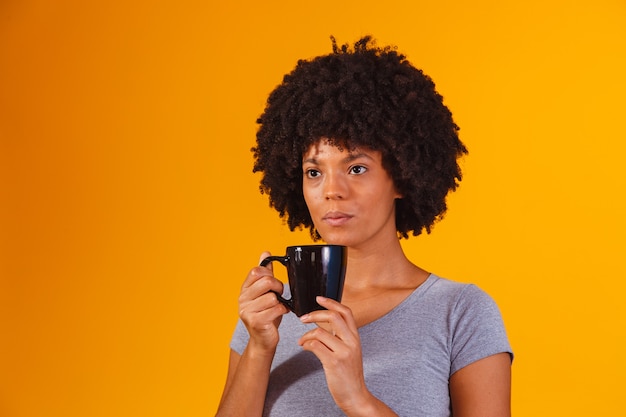 Afro-Frau trinkt Tee auf Gelb