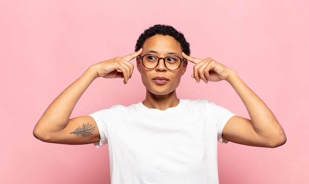 Afro joven mujer negra que se siente confundida o dudando, concentrándose en una idea, pensando mucho, buscando copiar el espacio lateral