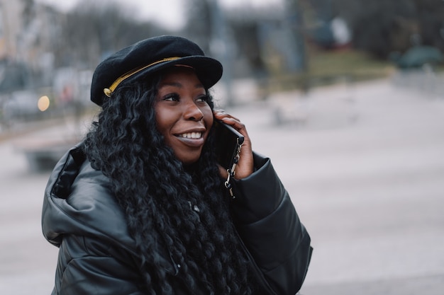 Afro-Mädchen benutzt das Telefon im Freien mit Technologie