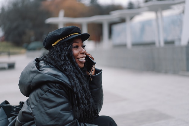 Afro-Mädchen benutzt das Telefon im Freien.