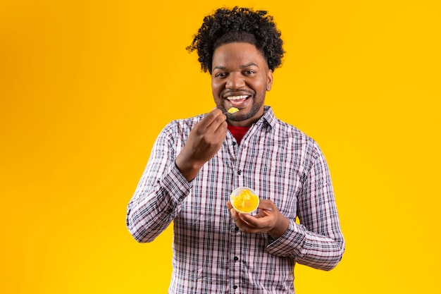 Afro-Mann im Juni-Party-Outfit, der ein köstliches Cural isst