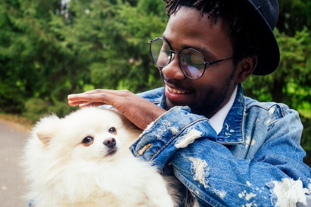 Afro-Mann umarmt seinen flauschigen Spitz im Park