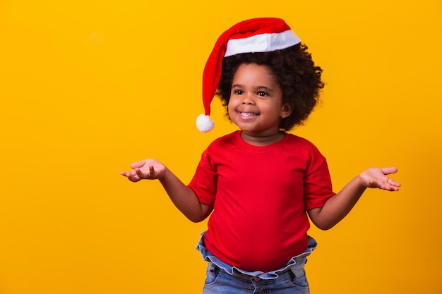 Afro menina em t-shirt vermelha e chapéu de papai noel vestida para o natal com espaço para apontar o texto.