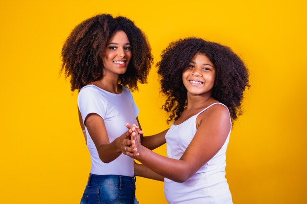 Afro-Mutter und Tochter tanzen auf gelbem Hintergrund