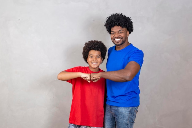 Afro padre e hijo celebrando con antecedentes grises felices por el día del padre o el día del niño