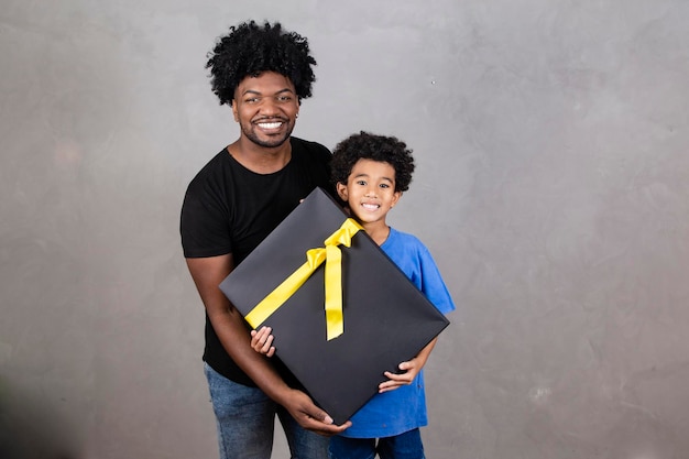 Afro pai e filho em fundo neutro com espaço livre para texto com presente