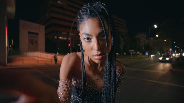 Afro trenzas modelo posando retrato de ciudad nocturna mujer de piel marrón mirando cámara